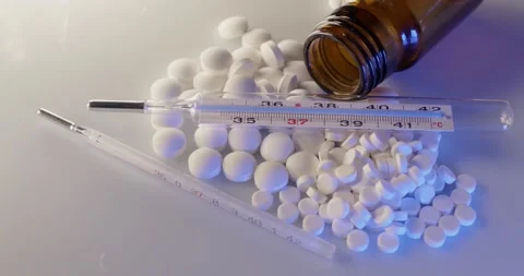 Fever Thermometer on top of white Pills and Medicine. Diagnostic and Cure Stock Footage 147933973
