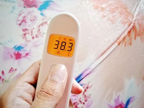 Fever Warning. Non-contact digital medical infrared forehead thermometer Re.. Stock Photos