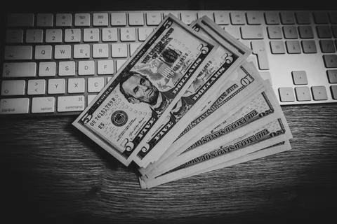 A few dollar notes lie on a computer keyboard on the desk 스톡 사진