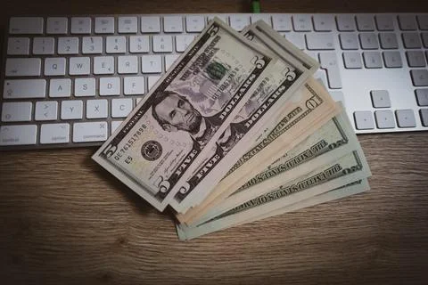 A few dollar notes lie on a computer keyboard on the desk Foto stock