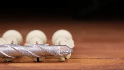 A few dowels and a drill bit on the concrete lay flat on the carpenter's wooden Stock Footage 73395531