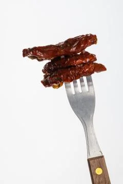 Few dried tomatoes impaled on fork Stock Photos