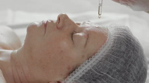 A few drops of rejuvenating serum are applied to an elderly woman's face Stock Footage 337124008