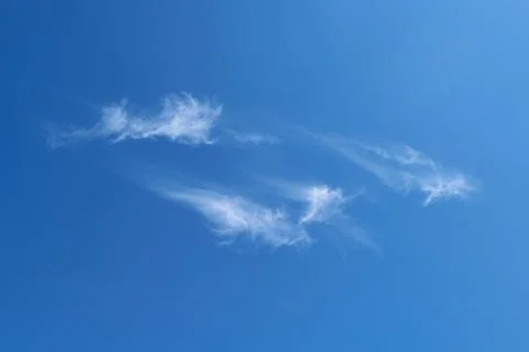 A few feathery clouds fly in the clear blue sky. Stock Photos