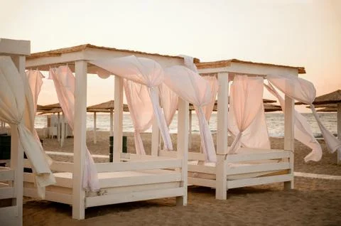 A few gazebos on the beach at sunset with evolving curtains, without people Photos