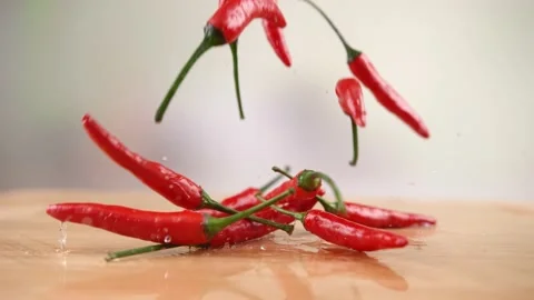 A few grains of fresh red chilies collide on a wooden board. 4K Footage Stock Footage 232987053