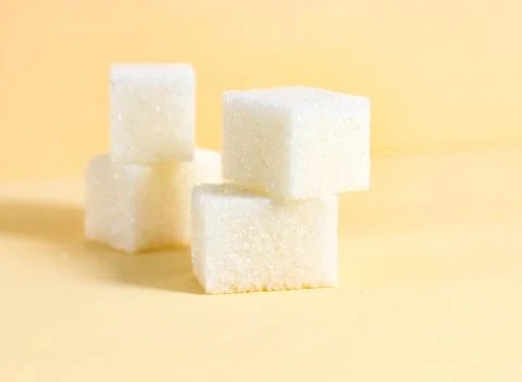 A few rectangular sugar cubes on a beige background. Stock Photos