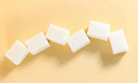A few rectangular sugar cubes on a beige background. Stockfoto's
