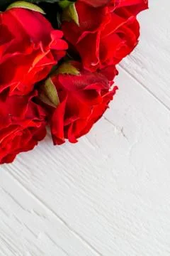 Few red roses in a corner on light wooden background with copyspace Stock Photos