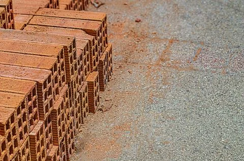 A few remaining rows of red mud bricks unloaded at the sidewalk and stacked f Foto stock
