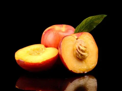 Few sliced nectarines with leaf isolated on black background Stock Photos