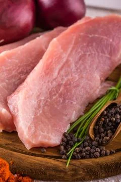 Few slices of raw pork meat on wooden plate with pepper Stock Photos