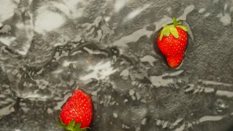 A few strawberries fall on a wet surface. Stock Footage 276838591