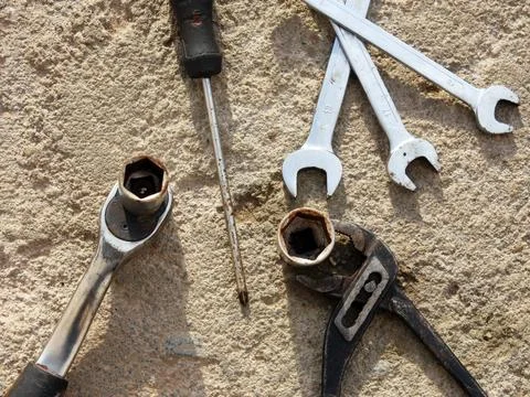 A few tools are on a concrete surface, one of which has a screwdriver on it Stock Photos