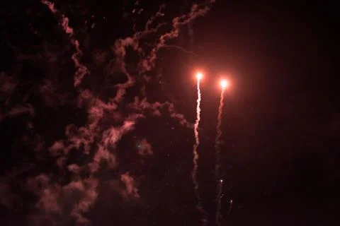 A few volleys of festive fireworks in the night sky, red-yellow. Stock Photos