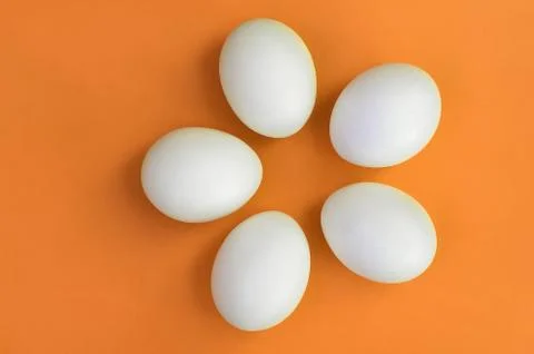 A few white easter eggs on a bright orange background Stock Photos