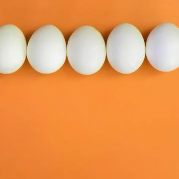 A few white easter eggs on a bright orange background Stock Photos