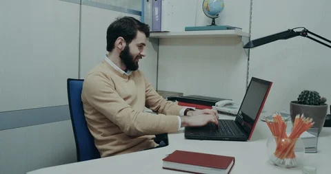Ffice worker , sitting at his desk tapping on the keyboard of his laptop , have Stock Footage 88402726