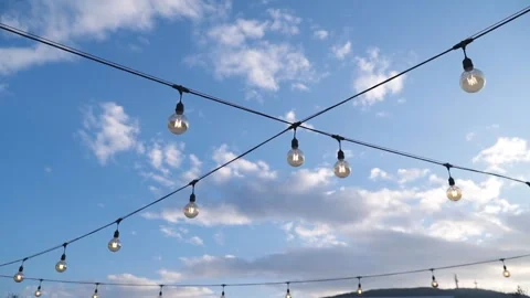 FHD Decorative lights on wire with blue sky and clouds - Wide Stock Footage 235025224