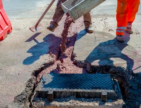 Fiber optic cables buried in a micro trench with concrete colored red by a wo Stock Photos