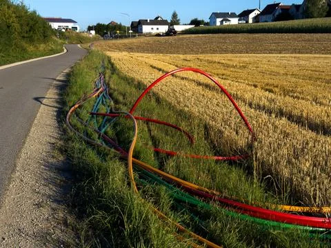 Fiber optic microduct cables laid along a country road leading to a rural vil Stock Photos