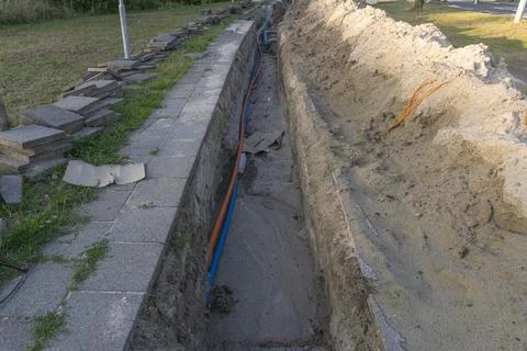 Fiber optic power cables laid inside a freshly dug ground trench outdoor Foto stock