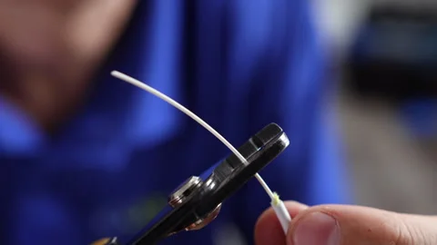A fiber technician strips and cleaves an optical fiber cable Stockbeeldmateriaal 312358764