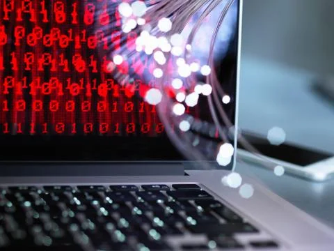 Fibre optics carrying data attacking a laptop computer which has a virus Foto stock
