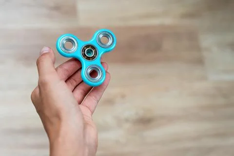Fidget spinner. Blue hand spinner, fidgeting hand toy rotating on child's han Stock Photos