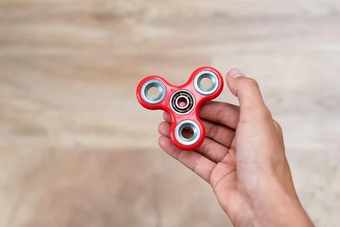 Fidget spinner. Red hand spinner, fidgeting hand toy rotating on child's hand Stock Photos