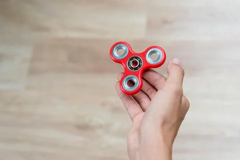 Fidget spinner. Red hand spinner, fidgeting hand toy rotating on child's hand Stock Photos