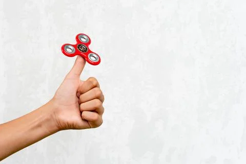 Fidget spinner. Red hand spinner, fidgeting hand toy rotating on child's hand Stock Photos