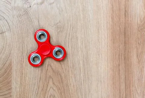Fidget spinner. Red hand spinner on wooden background. Free space for text. Stock Photos