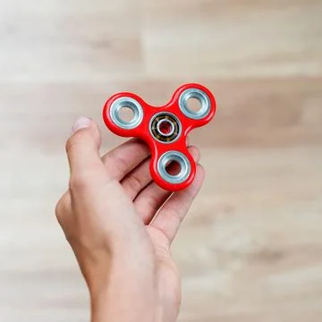 Fidget spinner. Red hand spinner, fidgeting hand toy rotating on child's hand 写真素材