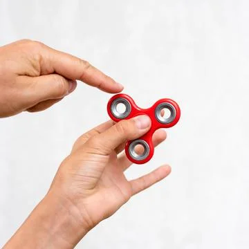 Fidget spinner. Red hand spinner, boys playing with fidgeting hand toy. Stres Stock Photos