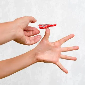 Fidget spinner. Red hand spinner, boys playing with fidgeting hand toy. Stres Stock Photos