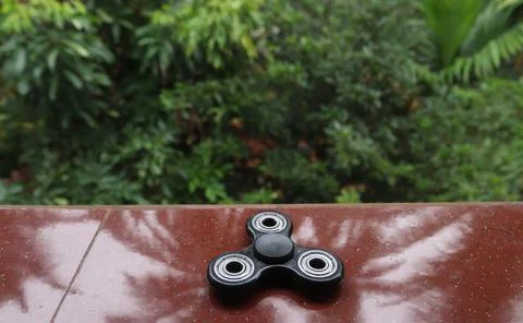 A fidget spinner resting on an open space Stock Photos