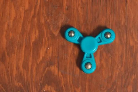 Fidget spinner on wooden desk in isolated background to fill with copy space Stock Photos