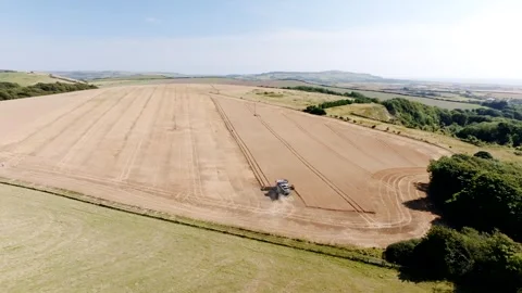 A field of brown grass with a tractor in the middle Stock Footage 297950704