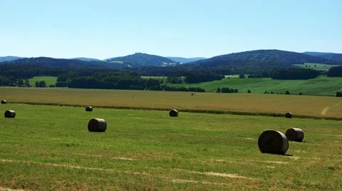 Field in countryside with haystack - forests in background - sunny day Stock Footage