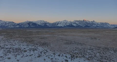 Field Covered in Snow Beneath Huge Mountains Grand Tetons Wyoming Winter Aerial Vidéo 87206873