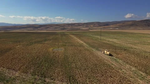 A field of dry grass with a tractor in the middle Stock Footage 331358098