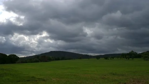 A field in front of a forest with clouds in the sky in time lapse. Stock Footage 138161429