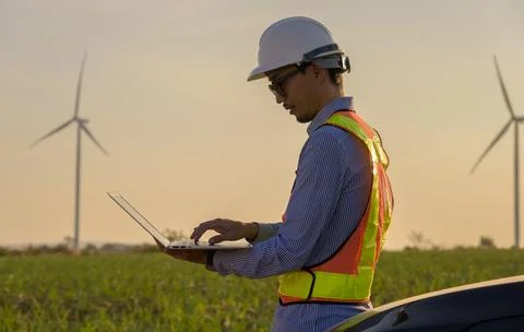 Field male engineer analyzing wind turbine performance data on laptop Stock Photos
