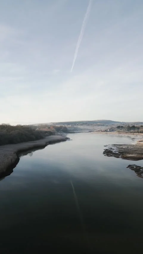 A field with a river running through it and a cloudy sky Stock Footage 298288936
