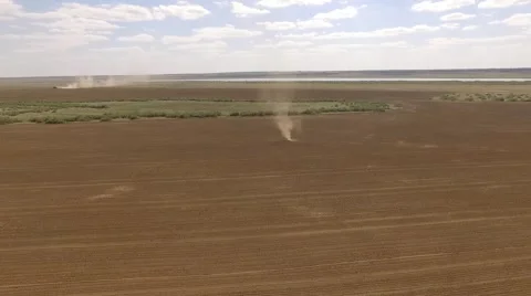 Field with tornado and a tractor at the background Stockbeeldmateriaal 68863378