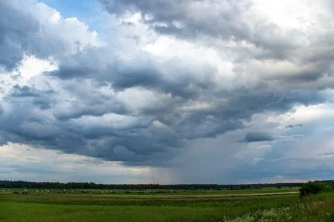 Field view, cloudy sky, rain in the distance Stock Photos