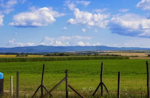 Fields against the backdrop of mountains and blue sky with clouds Stock Photos