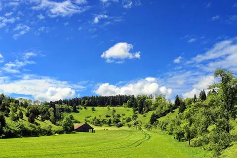Fields and meadows are enclosed by hills covered with trees Stock Photos