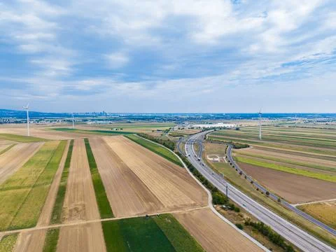 Fields and roads stretch across a landscape with wind turbines present. A nea Stock Photos